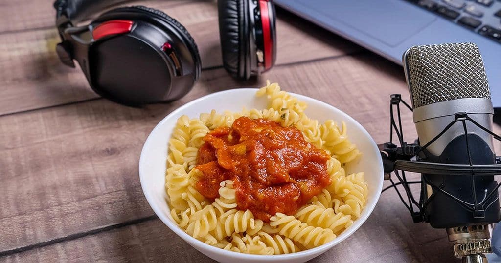 Past with tomato sauce next to headphones, a mic and a laptop during the production of the AIFS-focused Unfold Podcast by UC Davis