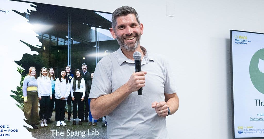 Dr. Ned Spang in front of a screen with a slide showing the students in his lab